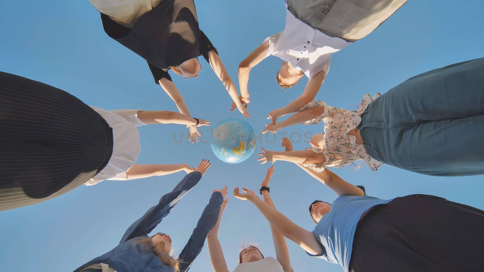 Friends hold and toss a geographic globe in their hands. The concept of keeping the world safe