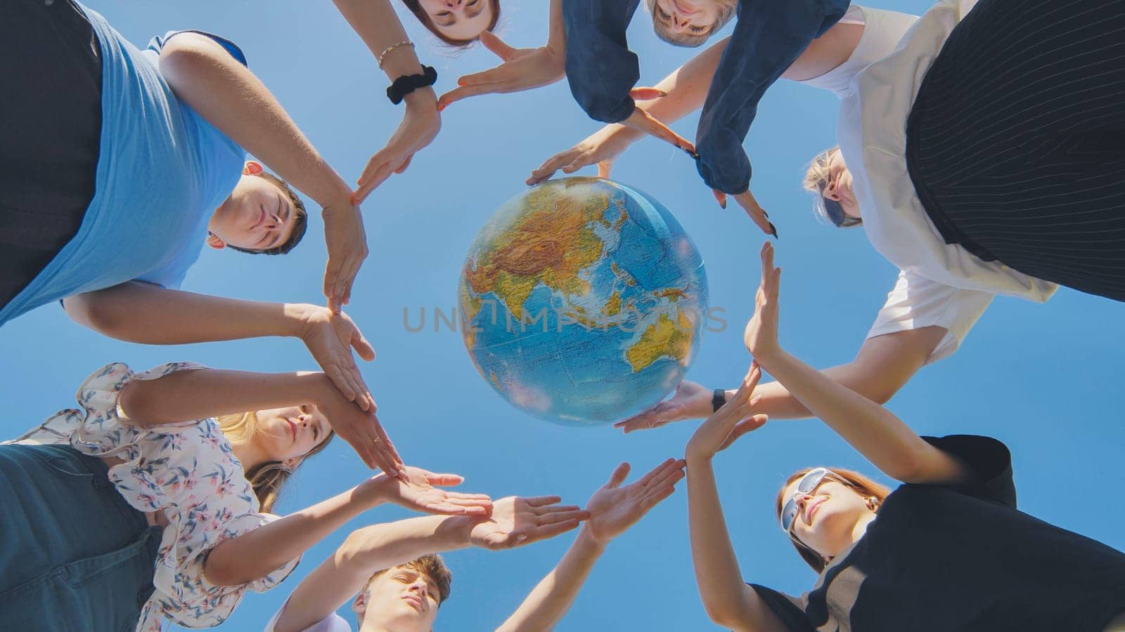 Young friends surround the globe of the world with their palms. The concept of preserving world peace