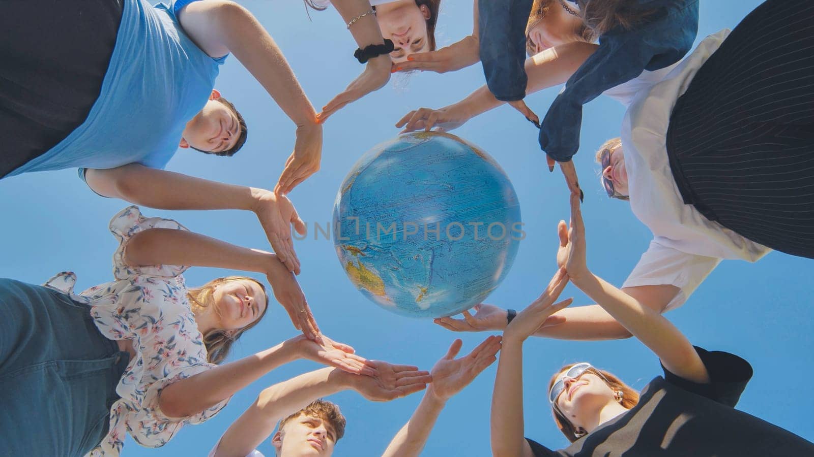 Young friends surround the globe of the world with their palms. The concept of preserving world peace