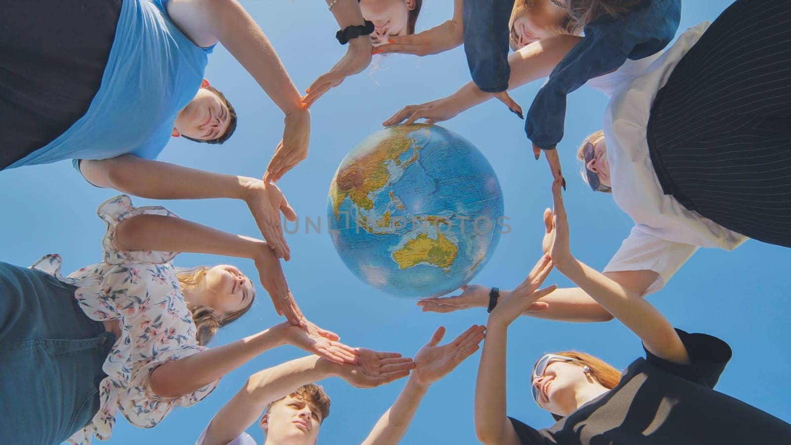 Young friends surround the globe of the world with their palms. The concept of preserving world peace