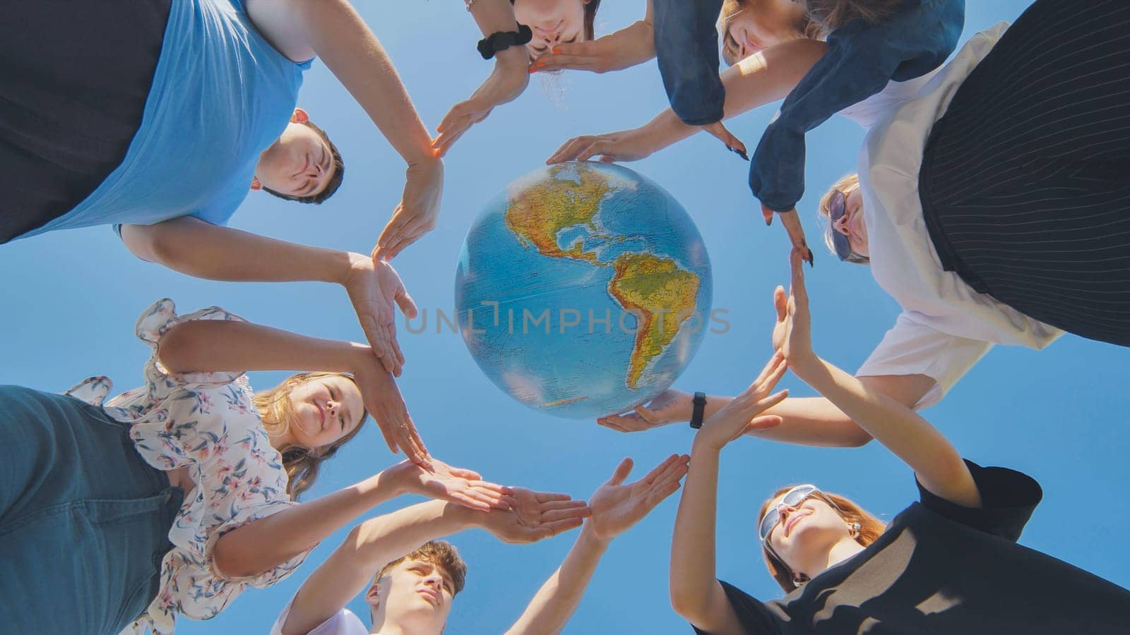 Young friends surround the globe of the world with their palms. The concept of preserving world peace. by DovidPro