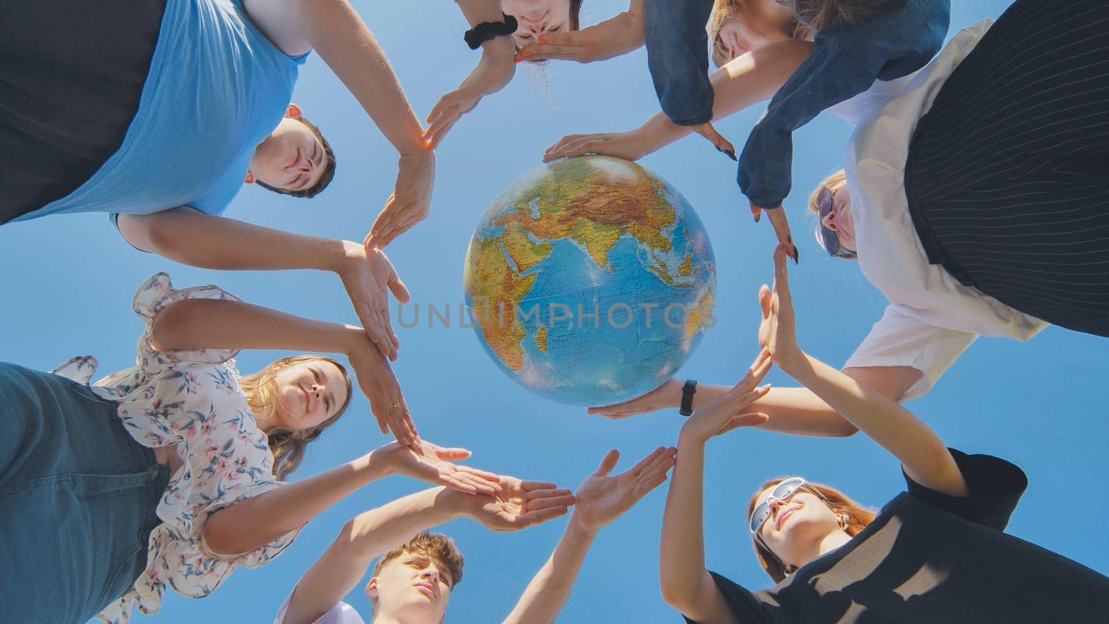 Young friends surround the globe of the world with their palms. The concept of preserving world peace