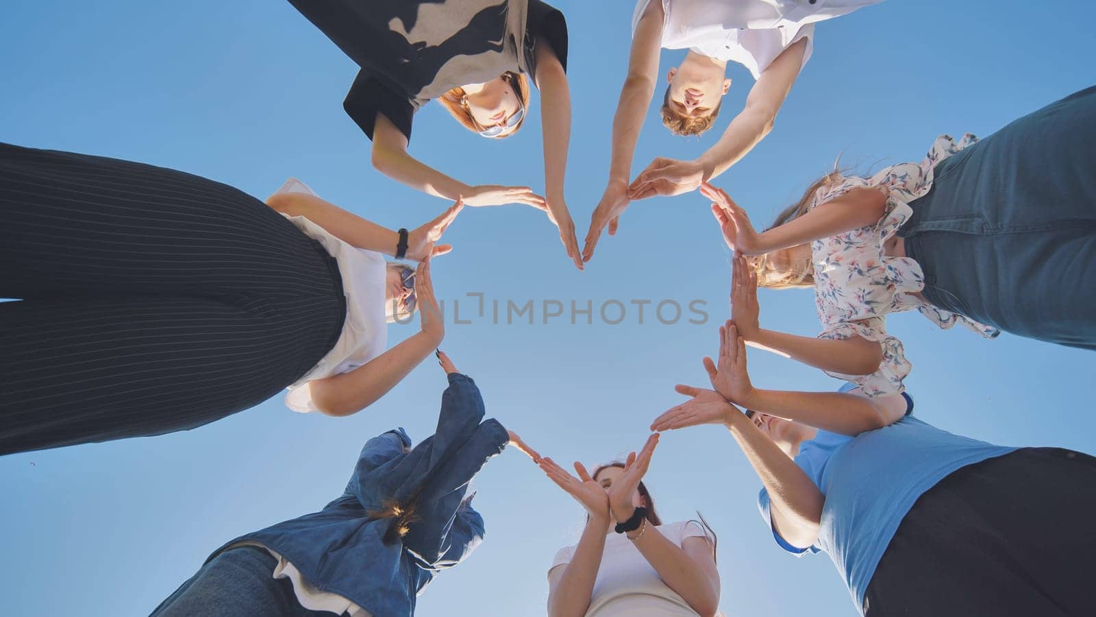 School children make a heart shape from their hands. by DovidPro