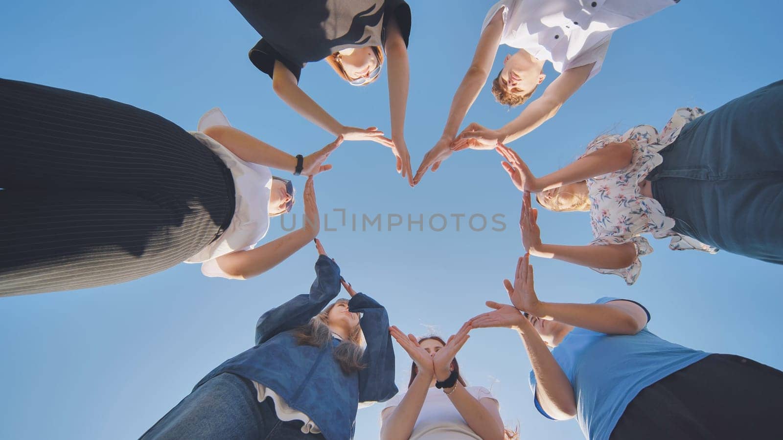 School children make a heart shape from their hands. by DovidPro
