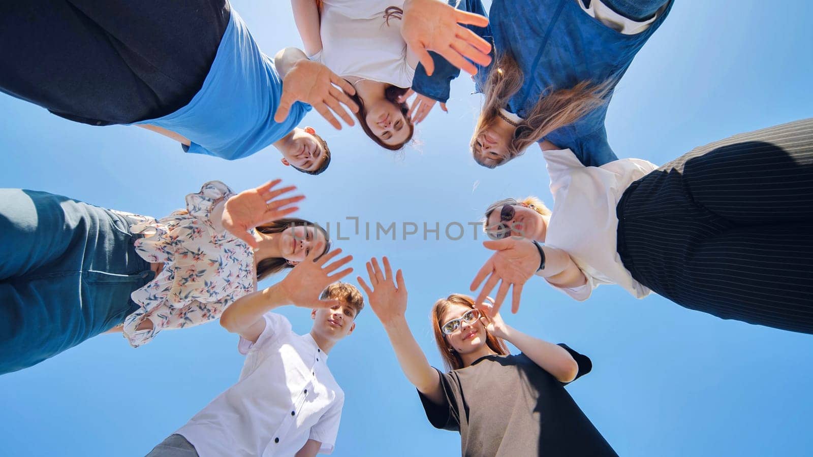 The young friends stand in a circle and wave their hands. by DovidPro