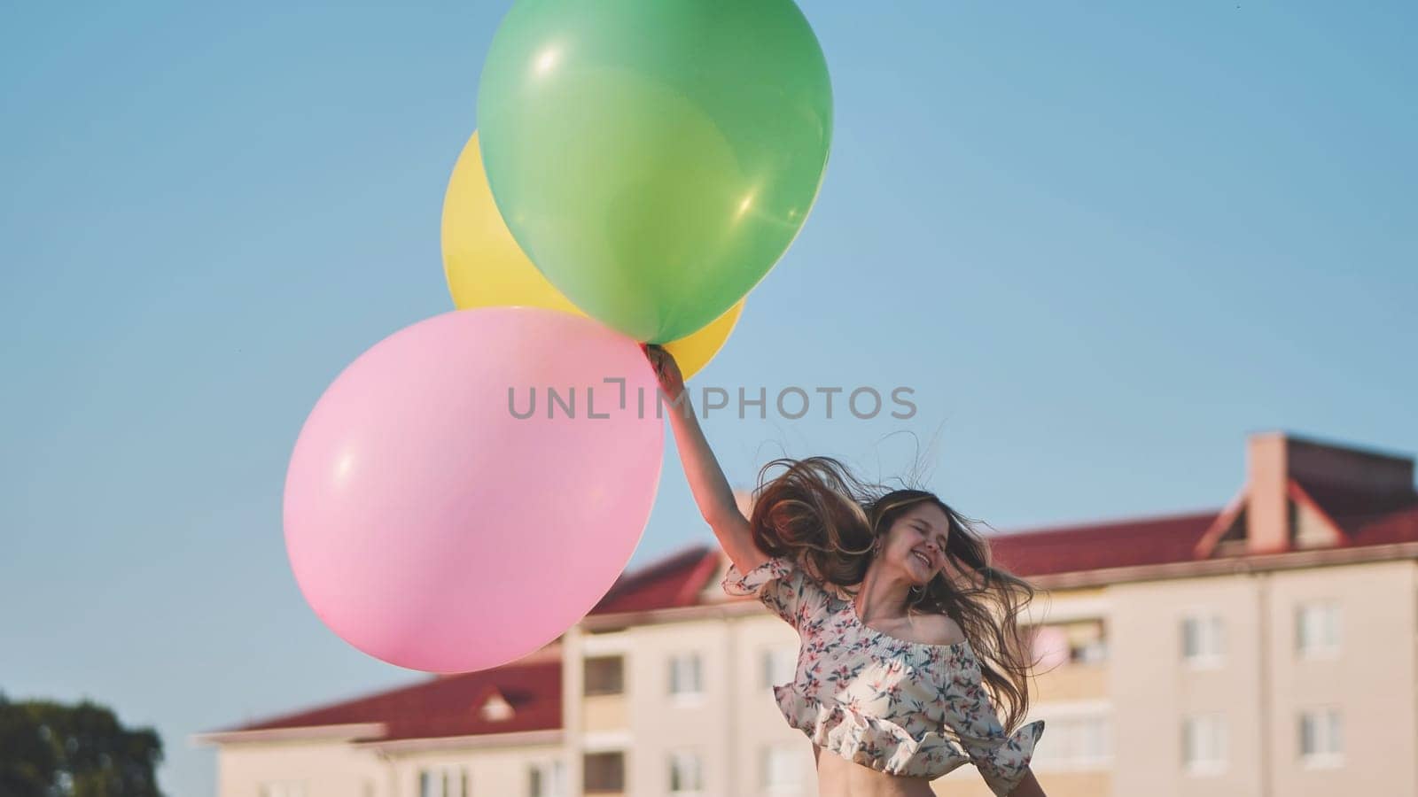 A girl happily poses with large with colorful balloons in the city. by DovidPro