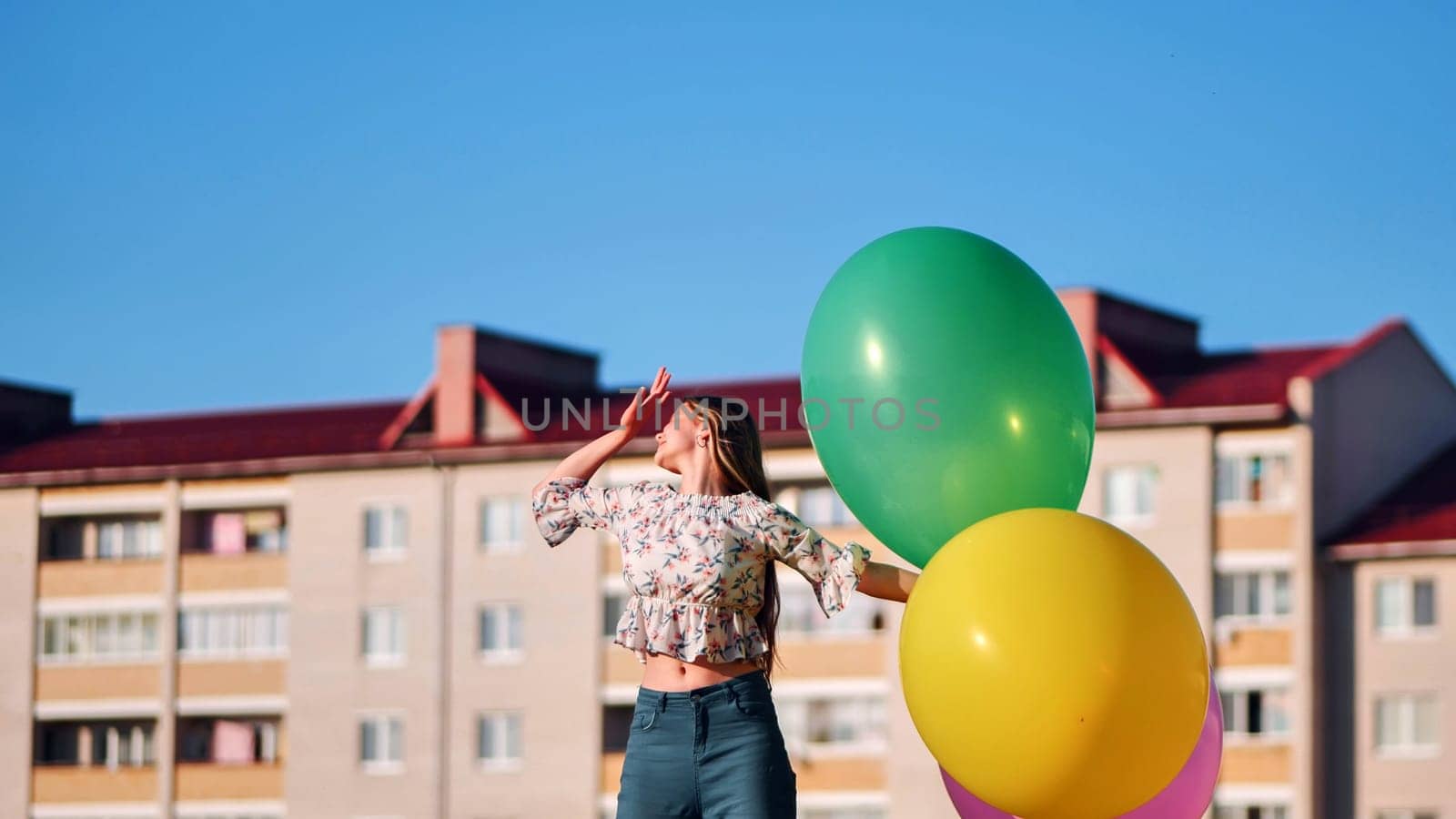 A girl happily poses with large with colorful balloons in the city