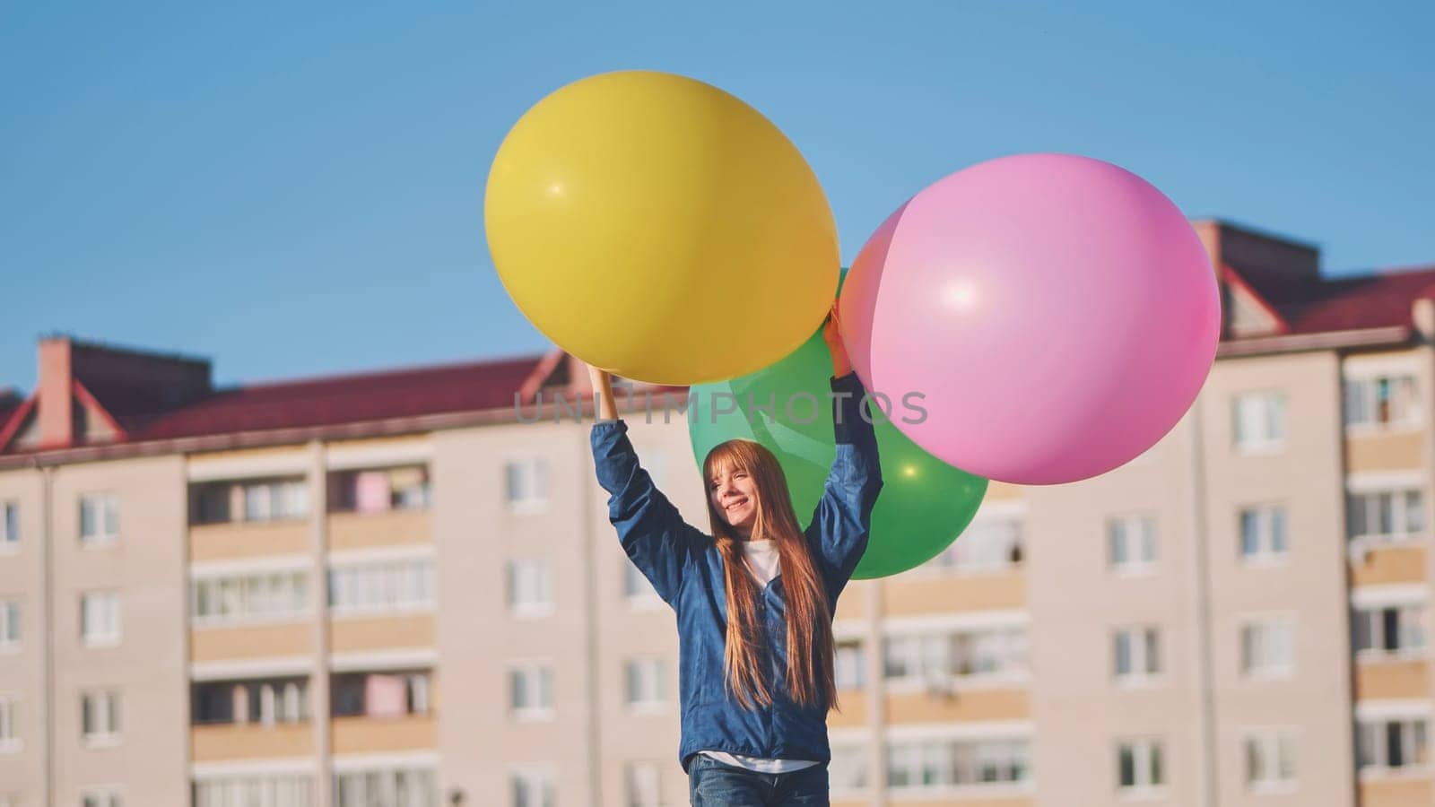 A girl happily poses with large with colorful balloons in the city. by DovidPro