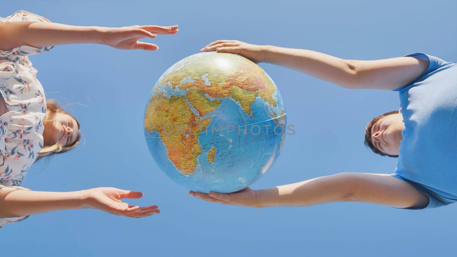 A girl and a guy swivels a globe of the world. The concept of peace and creation. by DovidPro