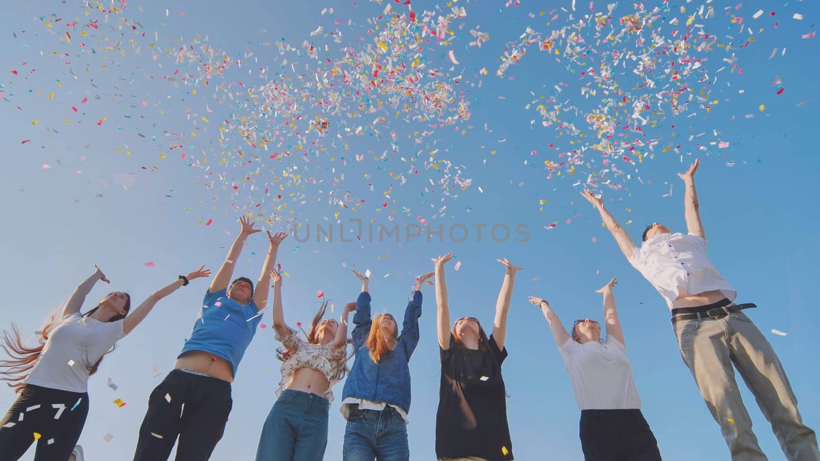 Friends toss colorful paper confetti from their hands