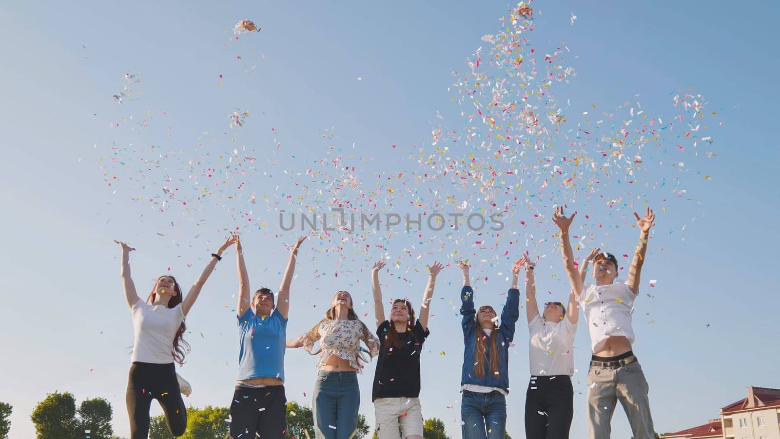 Friends toss colorful paper confetti from their hands. by DovidPro