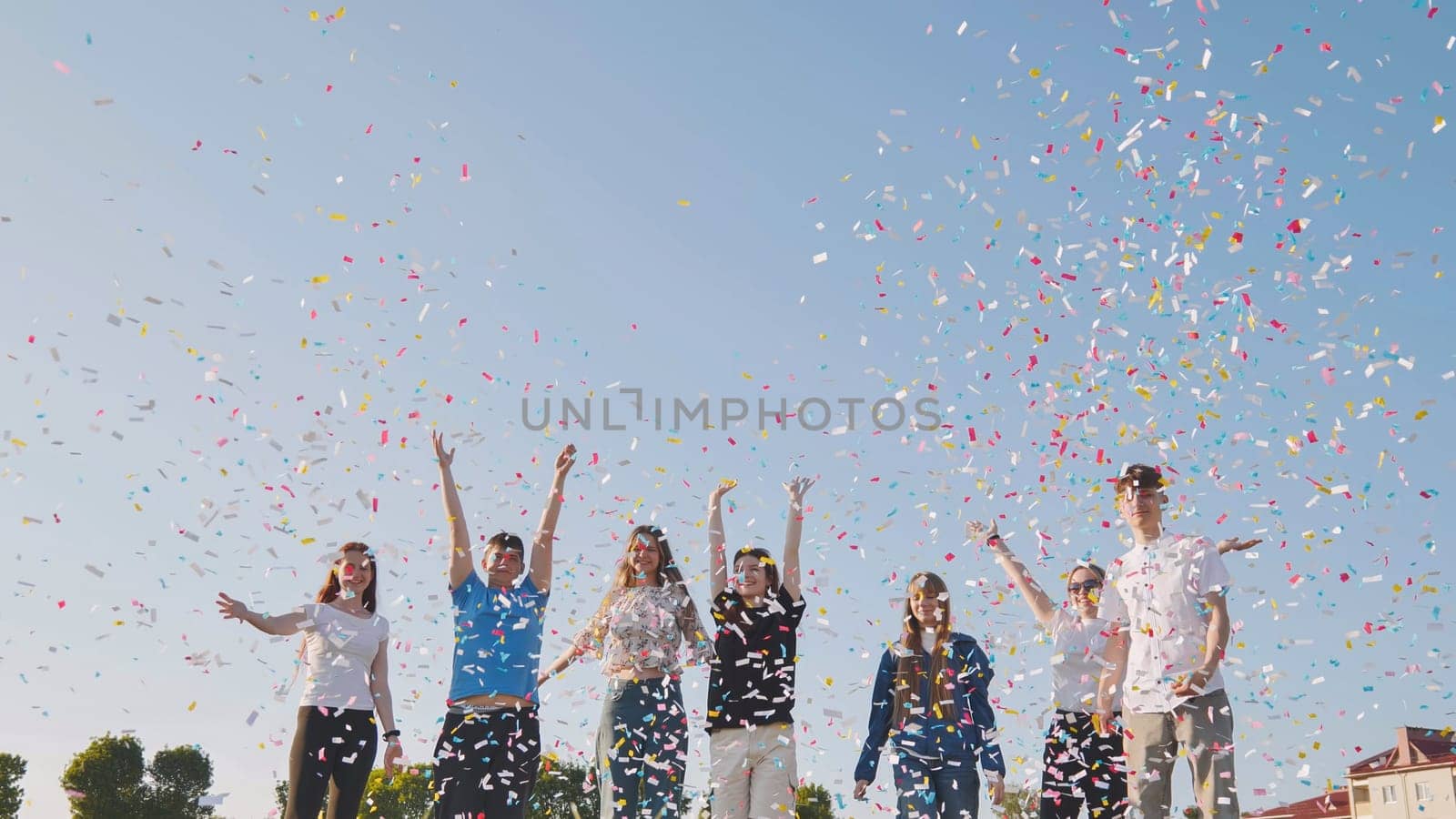 Friends toss colorful paper confetti from their hands. by DovidPro