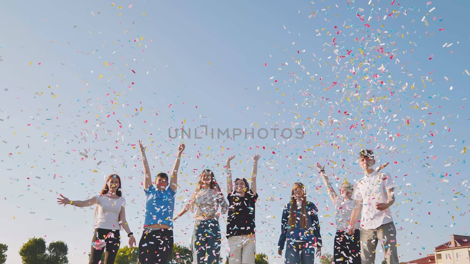 Friends toss colorful paper confetti from their hands. by DovidPro