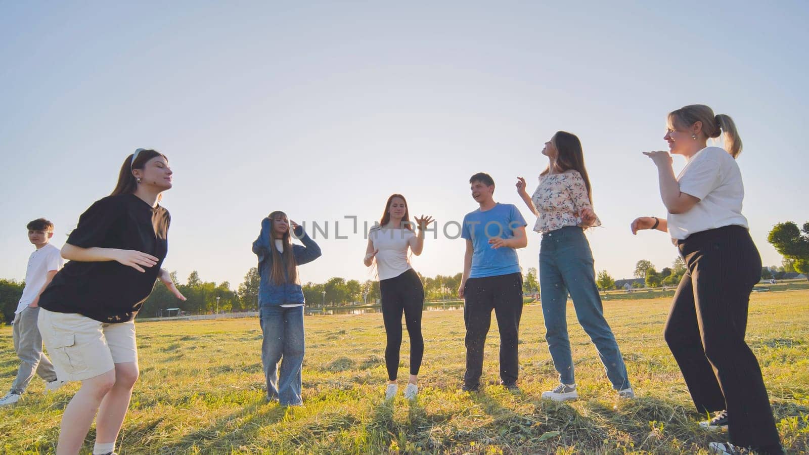 Funny jolly friends dancing in the city meadow in the evening. by DovidPro