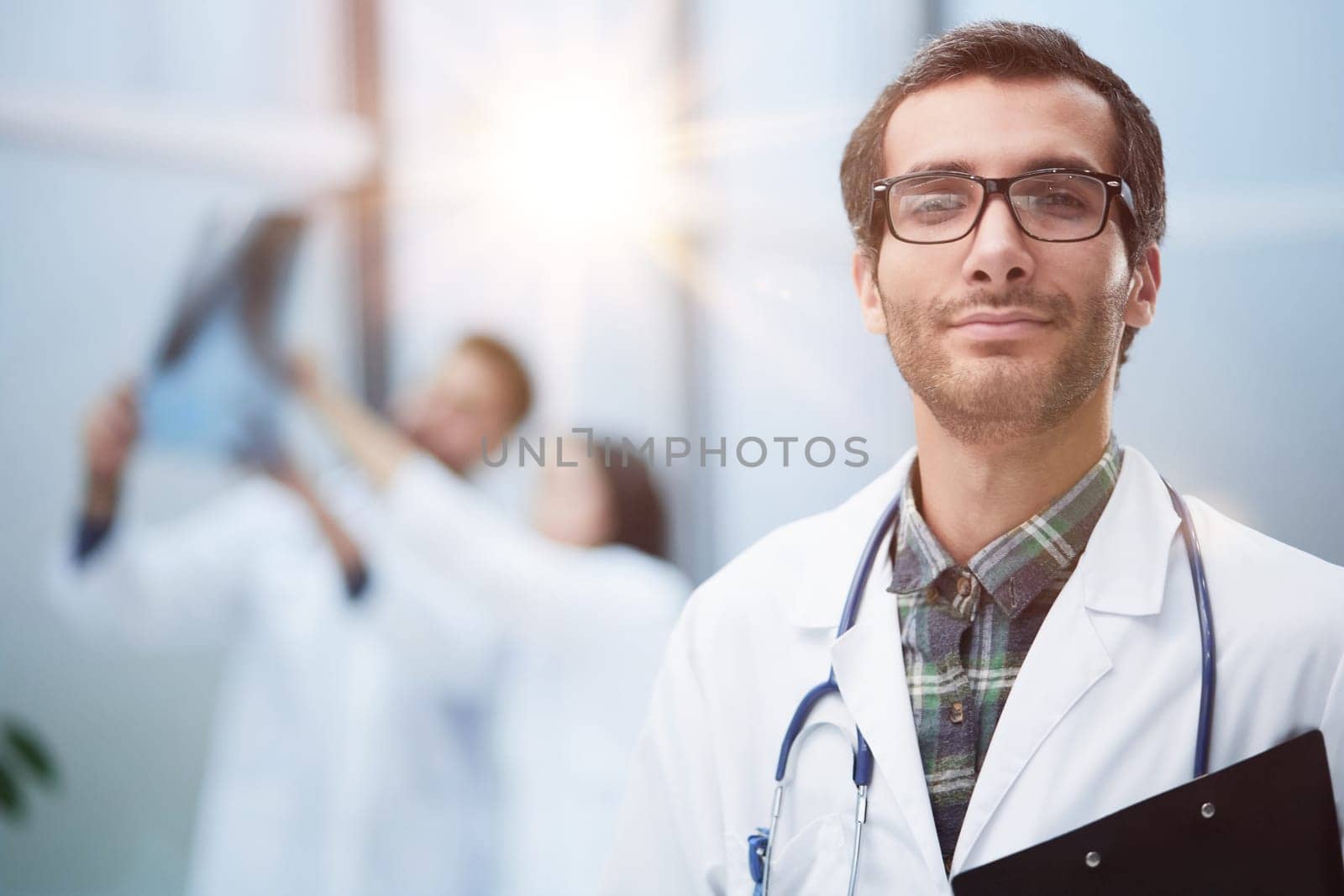 Confident doctor posing with, he is smiling at camera