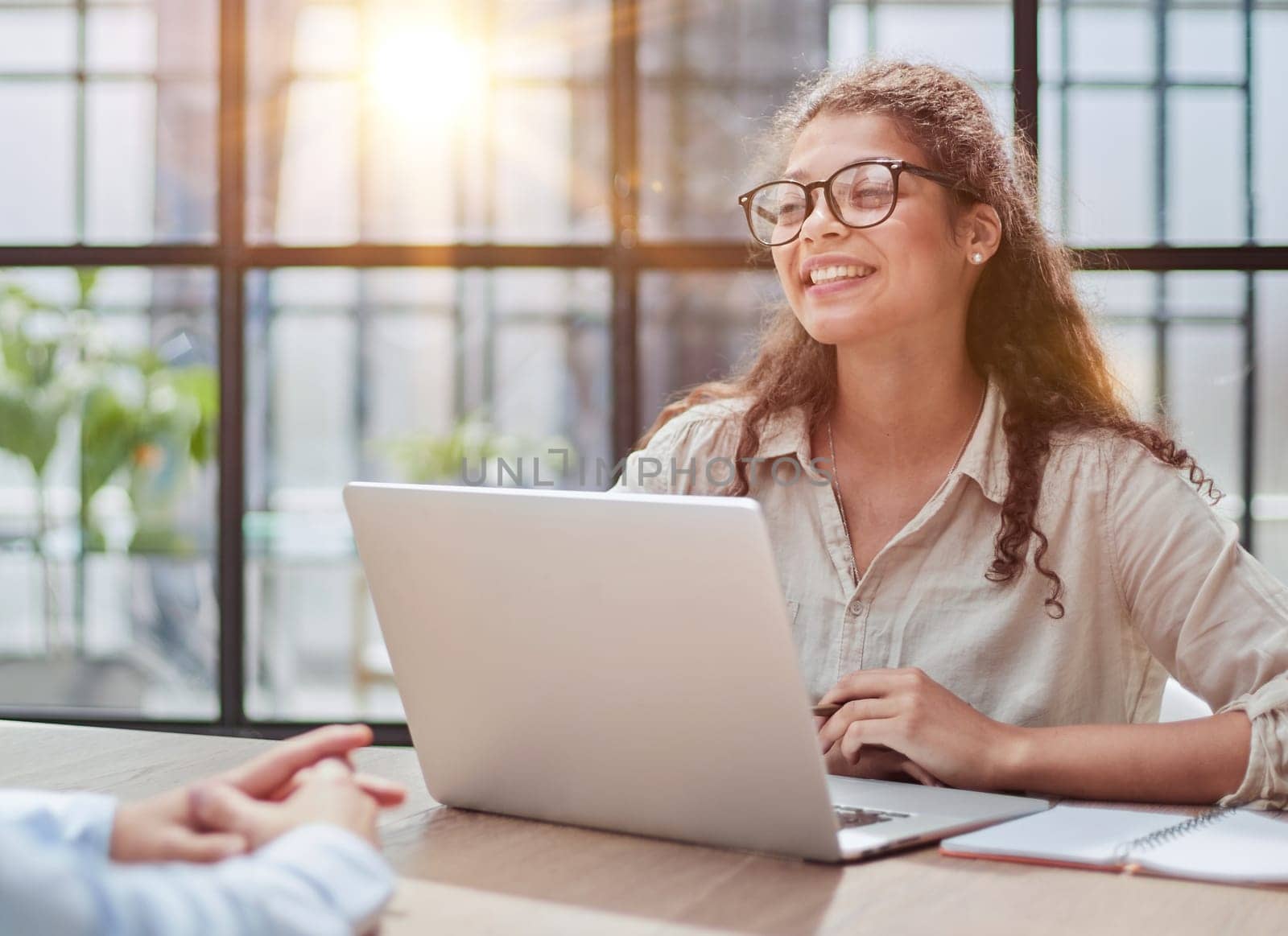 manager in glasses sitting at the table receives a client in the office looking at the camera