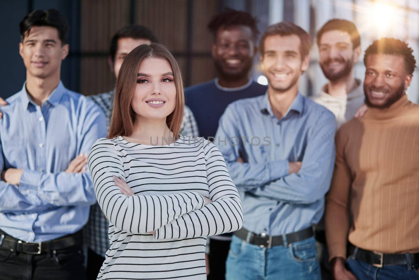 Smiling businesswoman looking at camera together with colleagues in the background