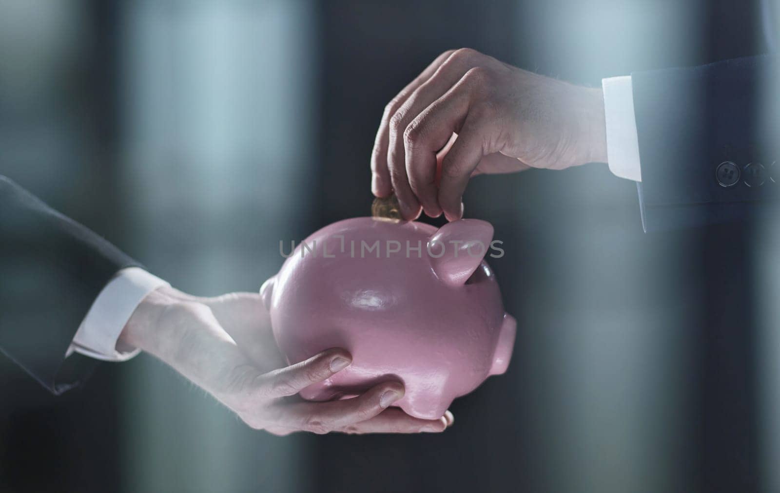 Hand puts a coin in a piggy bank on a black background by Prosto