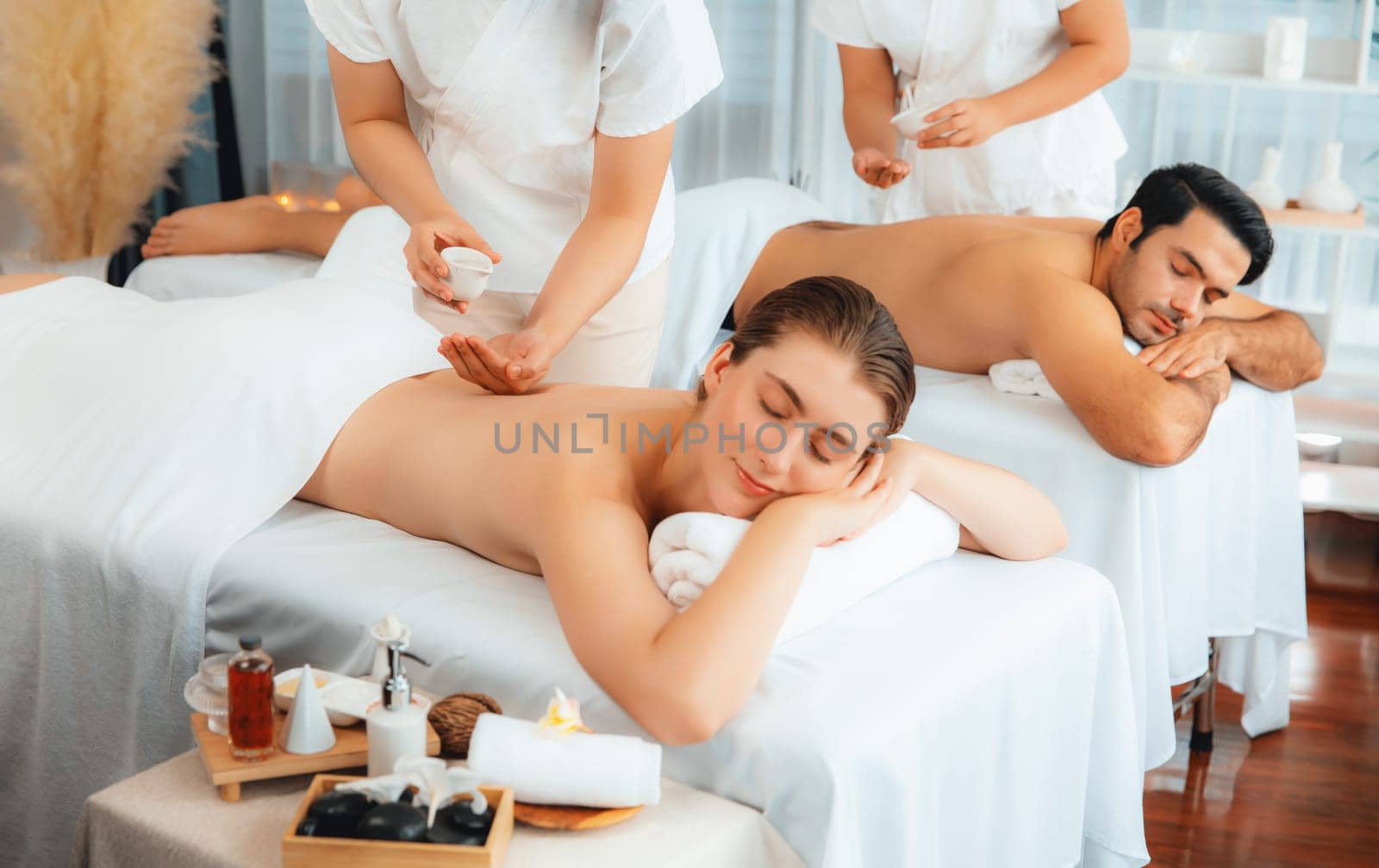 Caucasian couple customer enjoying relaxing anti-stress spa massage and pampering with beauty skin recreation leisure in day light ambient salon spa at luxury resort or hotel. Quiescent