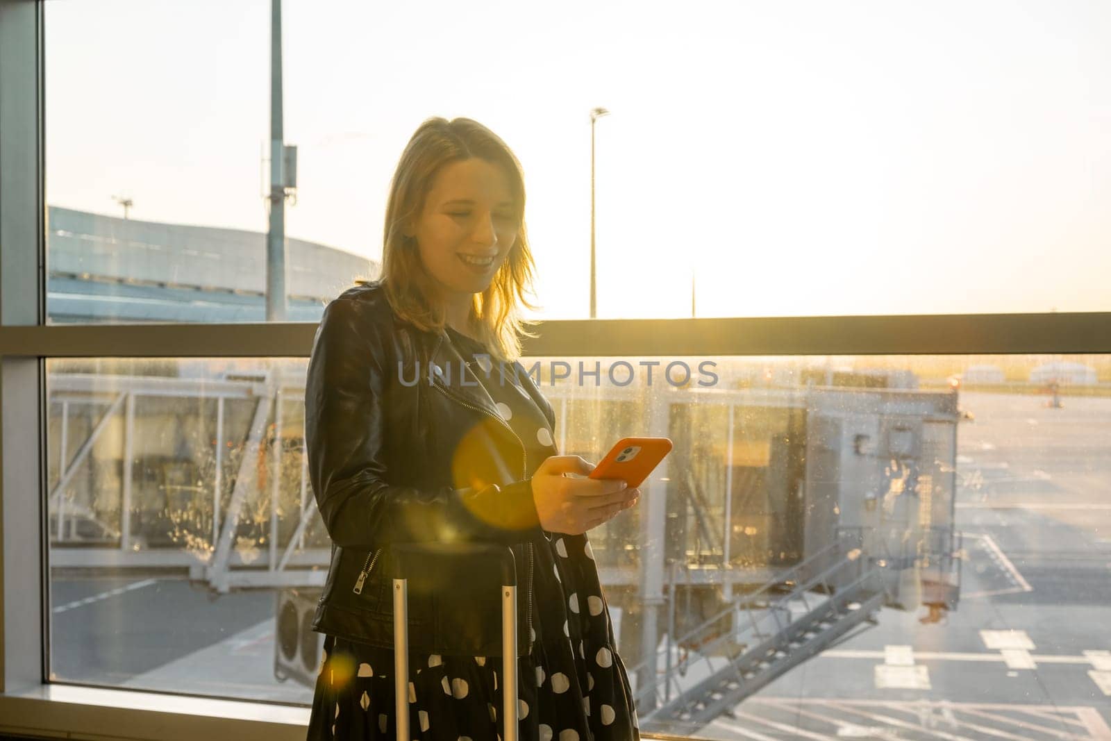 A young woman, checking her mobile phone, is prepared for boarding