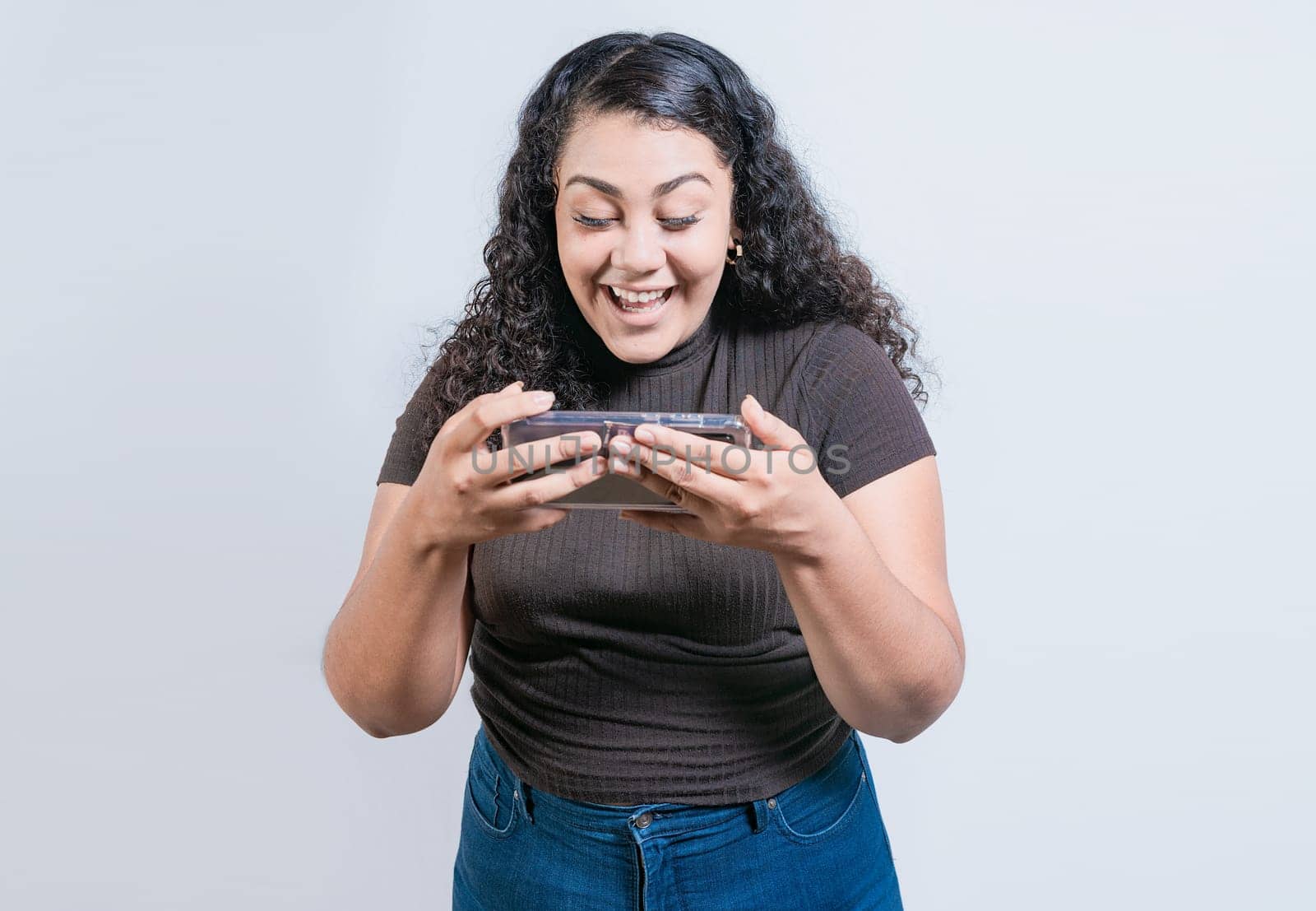 Happy latin girl using cell phone on isolated background. Cheerful people looking at a promotion on the phone isolated by isaiphoto