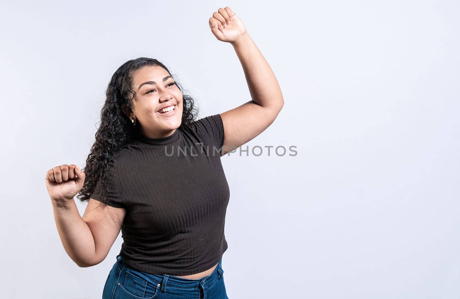 Excited latin girl raising arms celebrating victory. Happy young woman raising arms in victory gesture isolated. Winning people celebrating triumph by isaiphoto