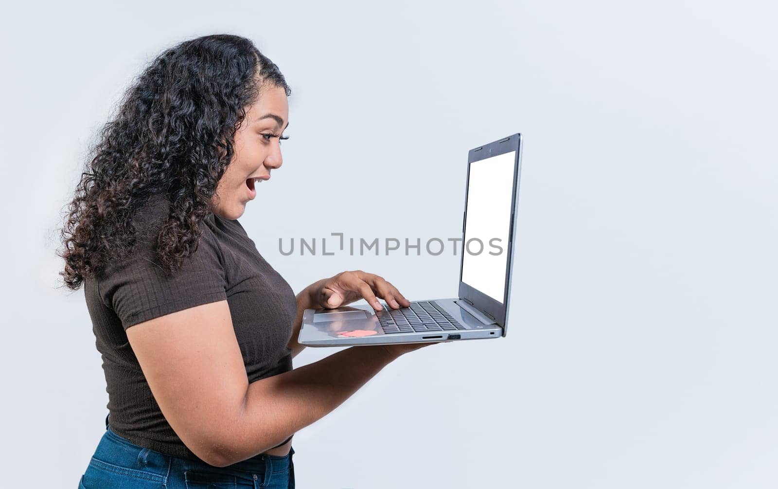 Surprised girl looking at an promotion on laptop screen isolated. Amazed latin woman using laptop isolated. Latin people looking offer promo on laptop isolated. by isaiphoto