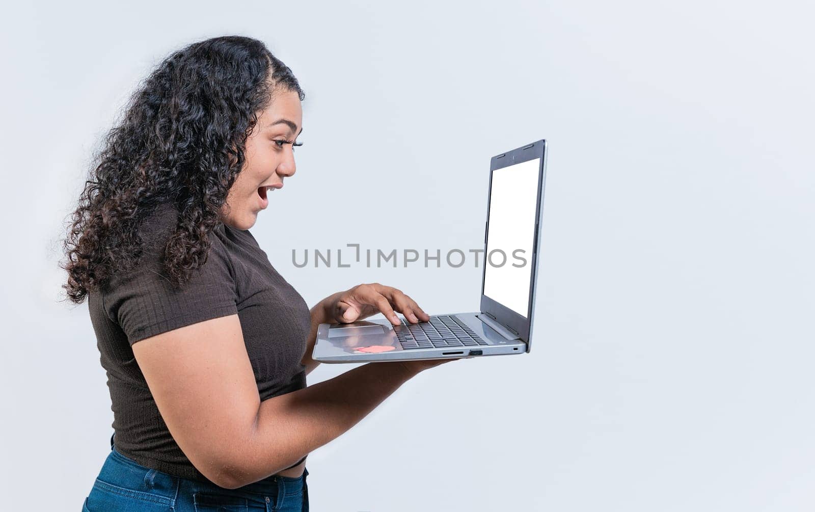 Surprised girl looking at an promotion on laptop screen isolated. Amazed latin woman using laptop isolated. Latin people looking offer promo on laptop isolated.