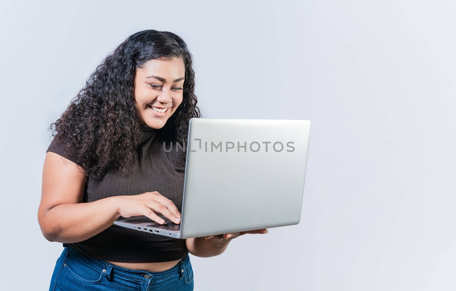 Smiling latin people looking offer promo on laptop isolated. Surprised girl looking at an promotion on laptop screen isolated. Amazed latin woman using laptop by isaiphoto