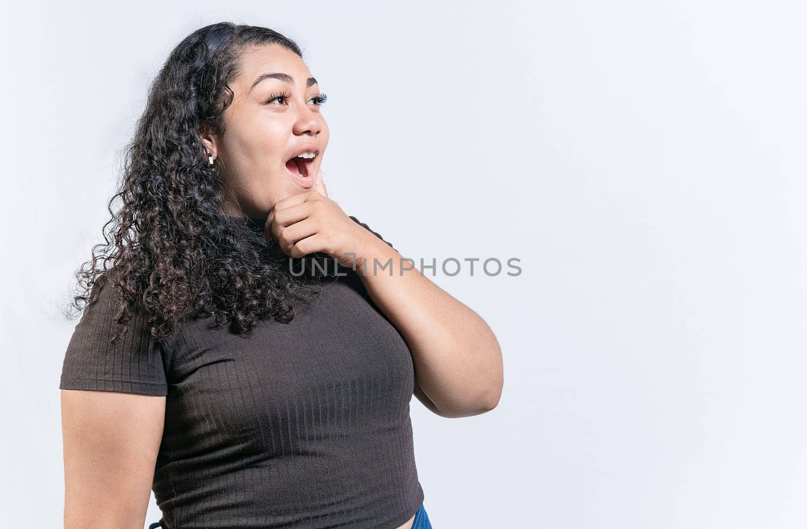Surprised woman holding chin looking at an advertisement to side. Amazed latin woman with hand on chin looking at side isolated by isaiphoto