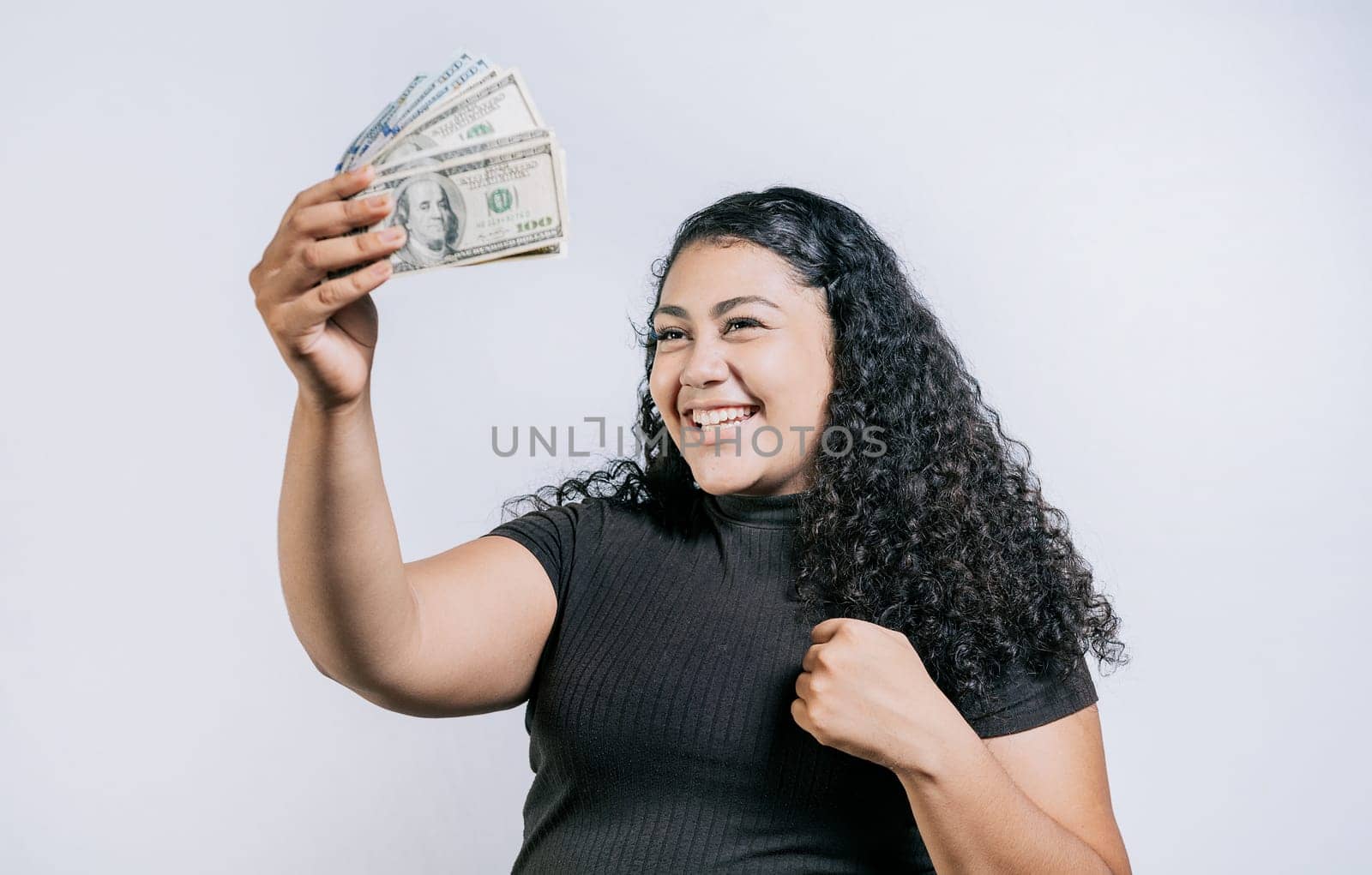 Excited latin girl holding dollar cash isolated. Victorious young woman holding money celebrating isolated