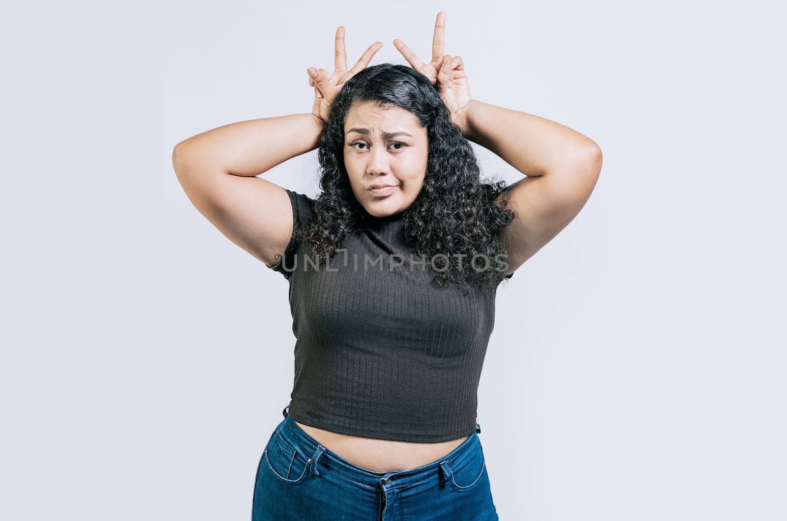 Funny girl making horns gesture with their fingers, gesture of betrayal. Funny young woman making horns gesture with fingers. Infidelity concept by isaiphoto