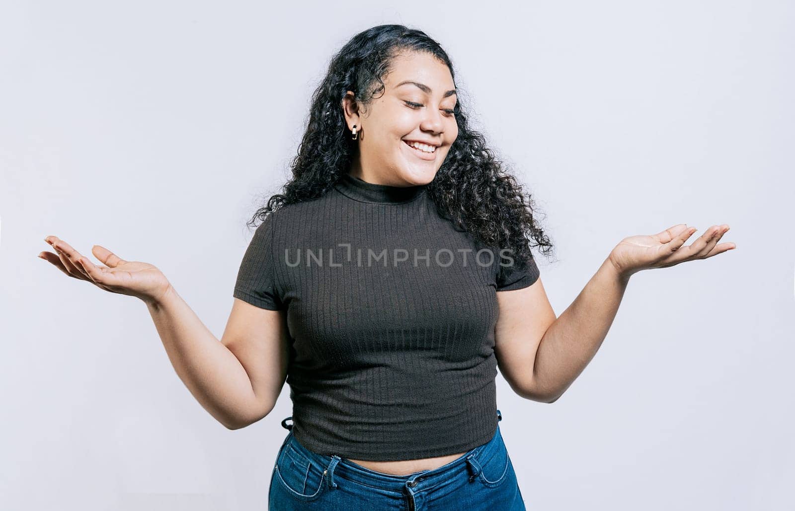 Smiling latin woman comparing with palms hands isolated. Happy girl balancing product with palms isolated by isaiphoto
