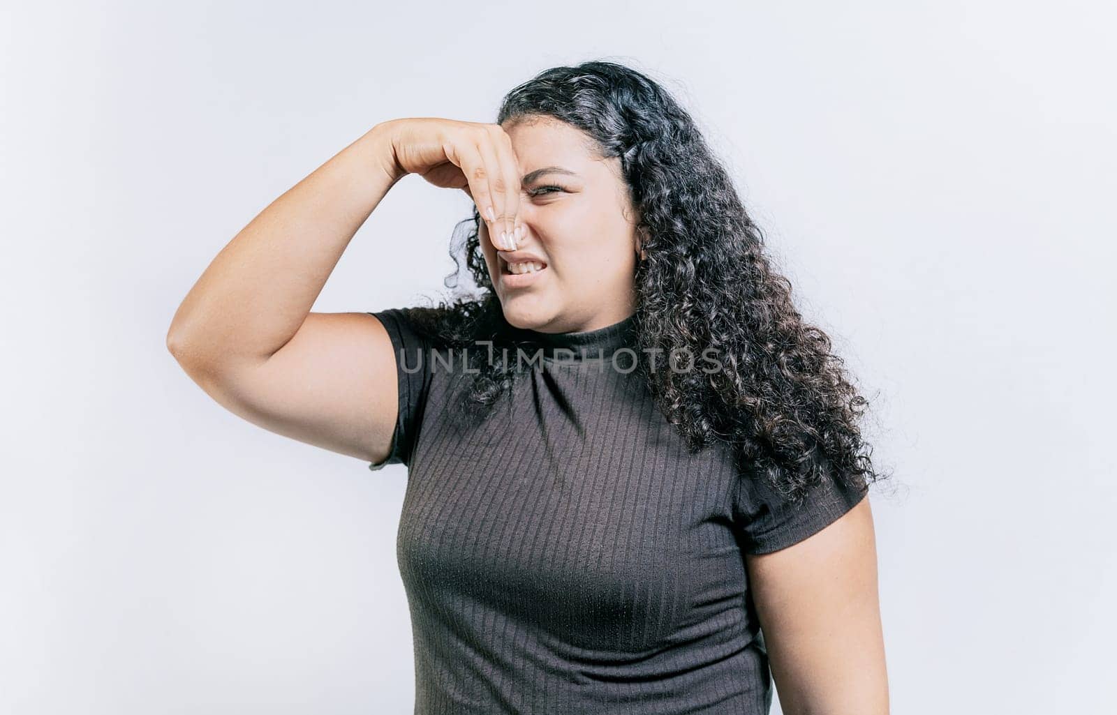 Young woman covering her nose from a bad smell isolated. Displeased girl holding her nose isolated. Disgust people covering nose by isaiphoto