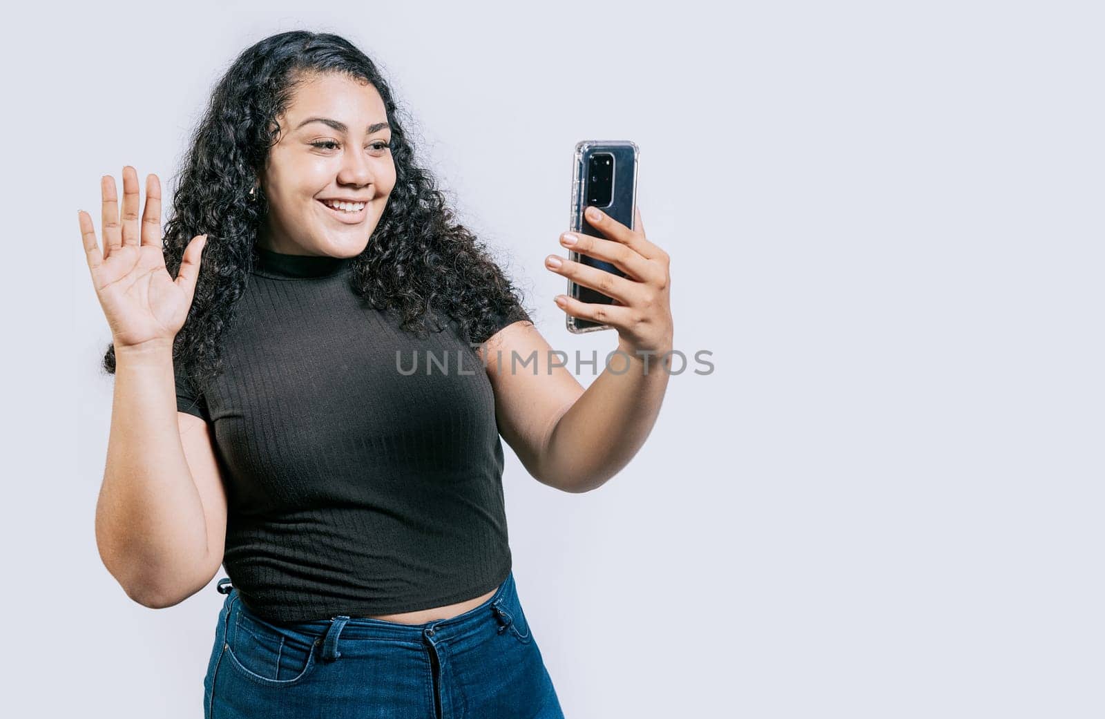 Smiling beautiful latin woman making a video call isolated. Happy Nicaraguan woman making a video call on isolated background by isaiphoto