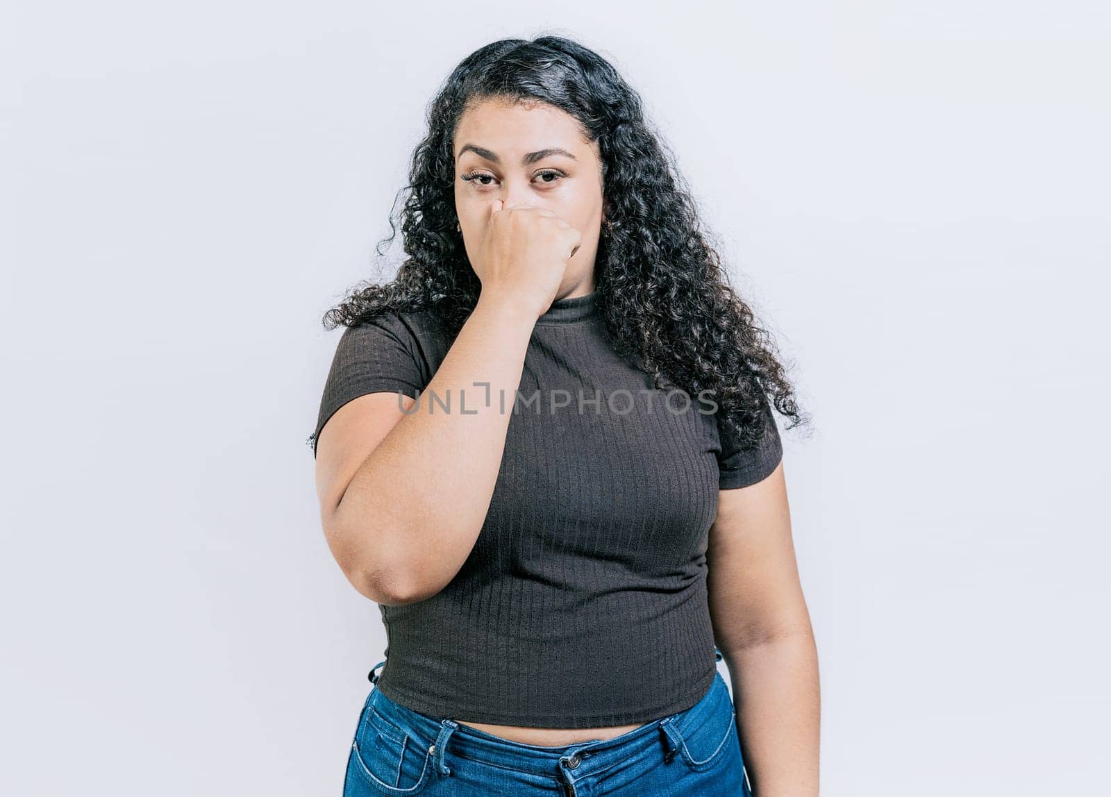 Displeased girl holding her nose isolated. Disgust people covering nose. Latin woman covering nose from a bad smell isolated by isaiphoto