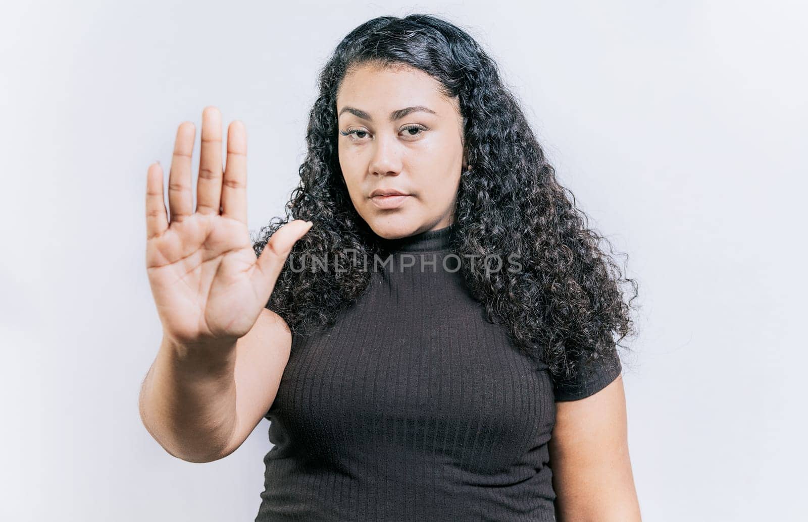 Close up of woman gesturing stop with the palm of hand isolated. People gesturing stop isolated. Latin woman gesturing stop with palm hand isolated by isaiphoto