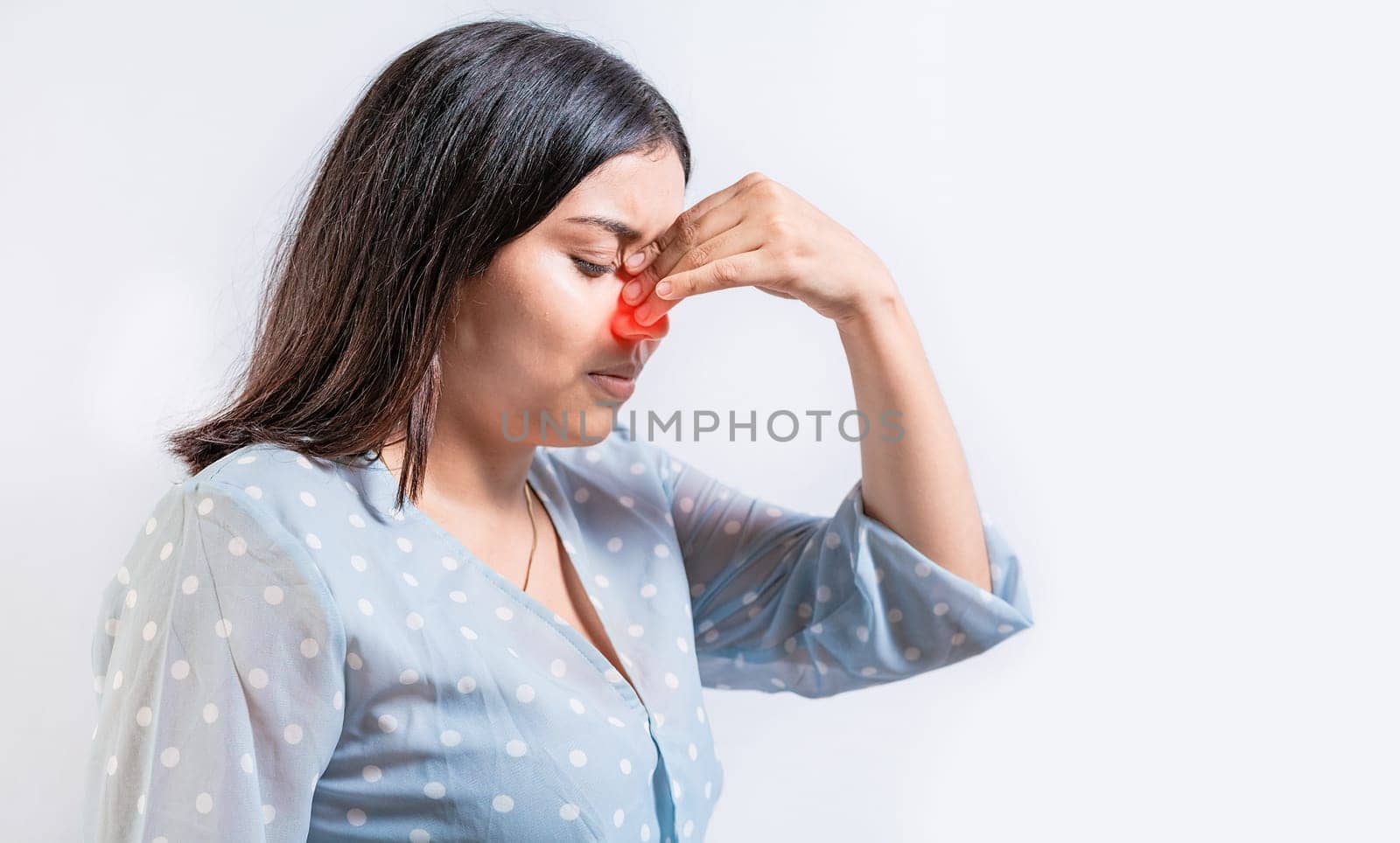 Young woman with pain touching nose. Person with nasal bridge pain, Girl with nasal bridge headache. Sinus pain concept by isaiphoto