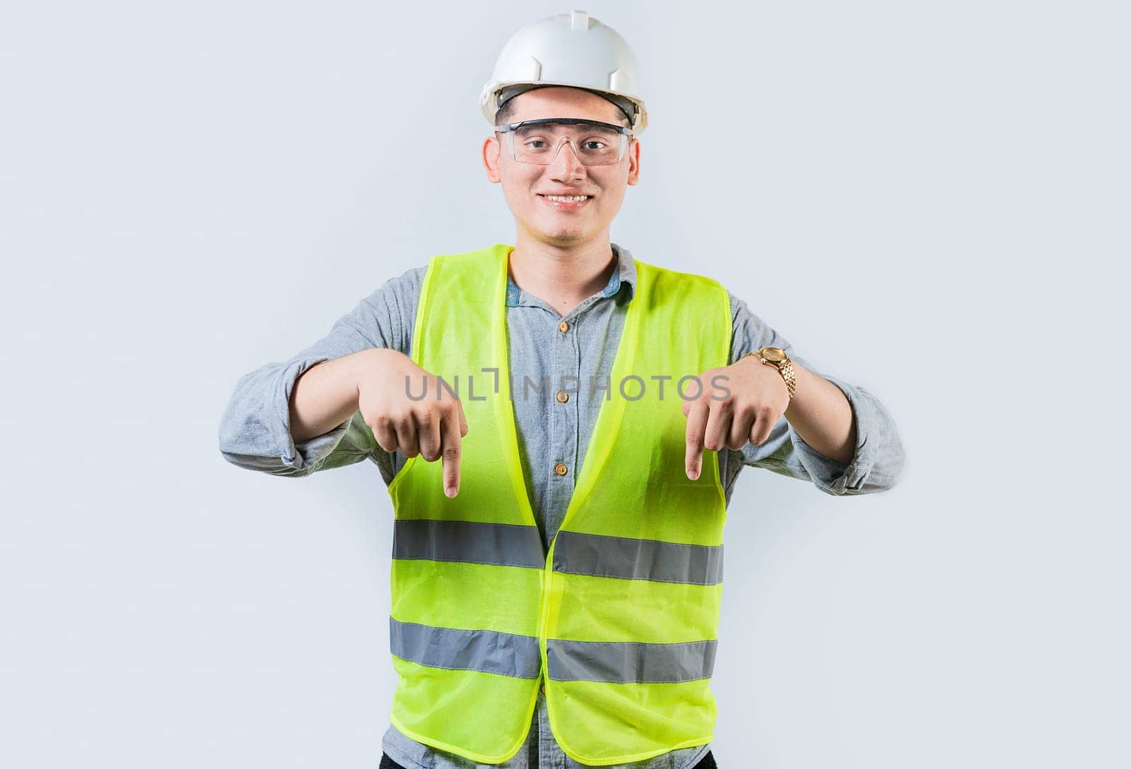 Smiling engineer pointing advertising down isolated. Smiling friendly engineer pointing down isolated by isaiphoto
