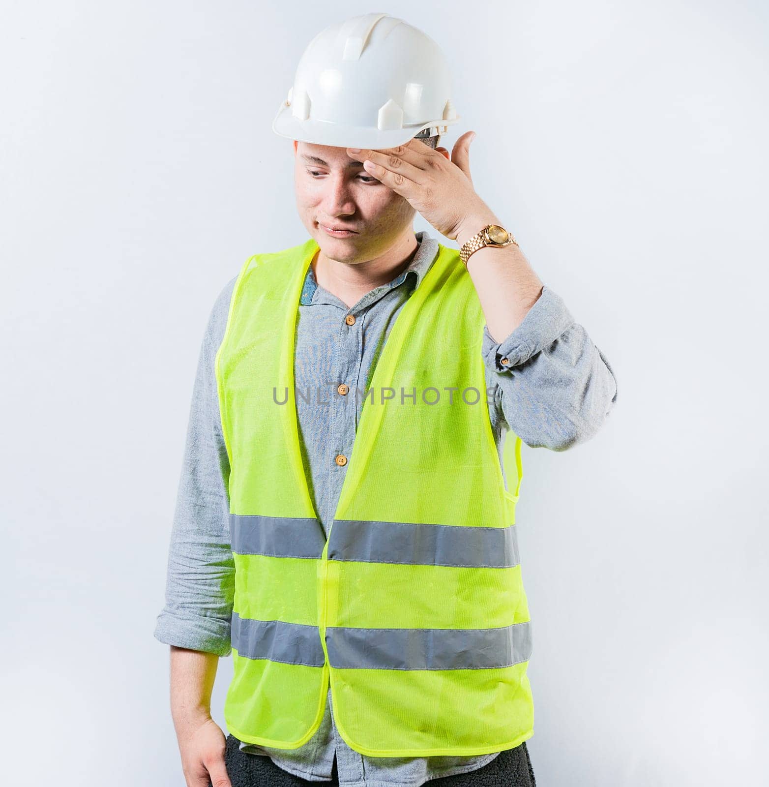 Worried young engineer holding forehead isolated. Frustrated young engineer holding forehead and looking down. Worried male engineer man holding forehead by isaiphoto