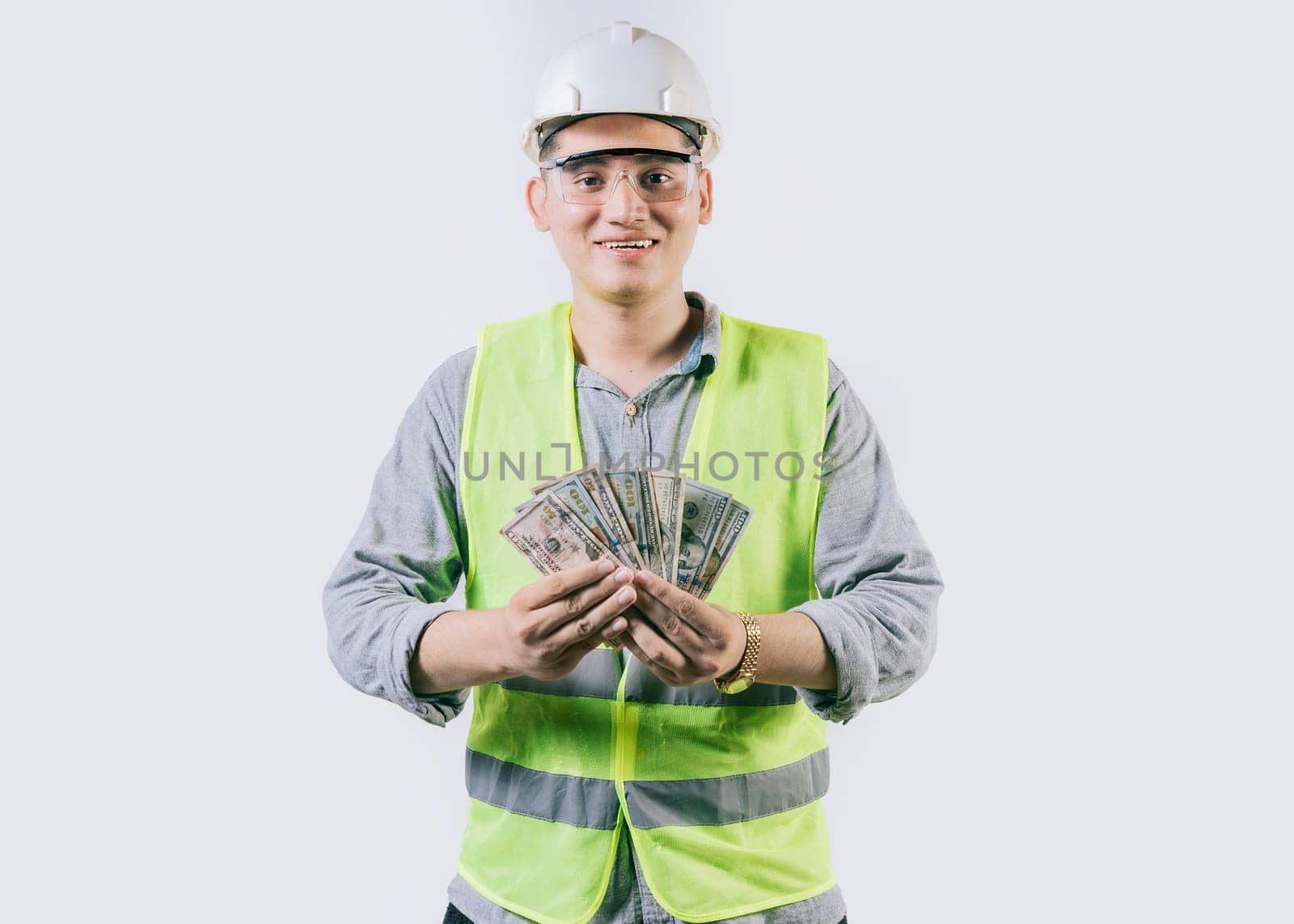 Portrait of happy engineer in helmet holding money isolated. Cheerful male engineer holding money on isolated background by isaiphoto