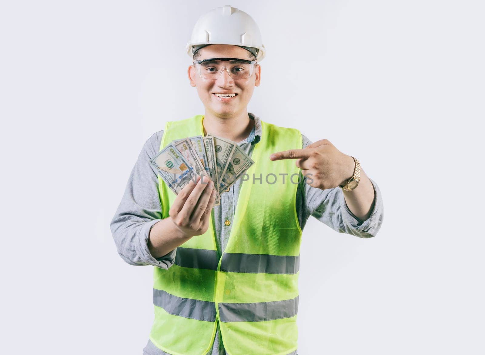 Smiling engineer builder holding and pointing money isolated. Handsome engineer showing and pointing money isolated by isaiphoto