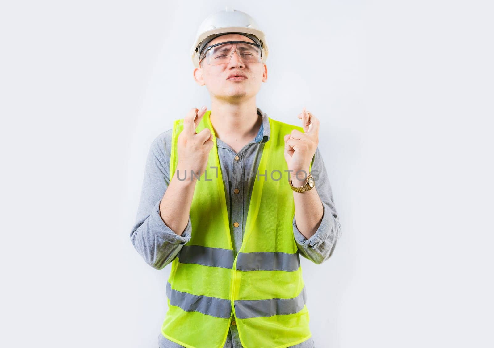 Portrait of young engineer making a wish. Handsome engineer crossing fingers making a wish by isaiphoto