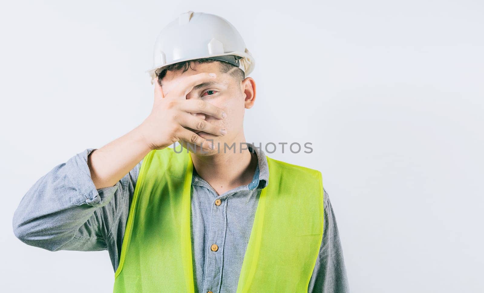 Man engineer with irritated eyes isolated. Young engineer with conjunctivitis on isolated background  by isaiphoto