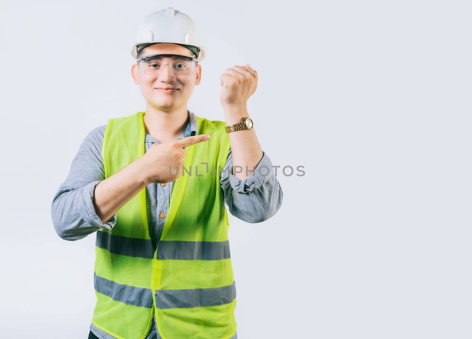 Smiling engineer pointing at his wrist watch isolated. Young engineer pointing and showing his wrist watch by isaiphoto