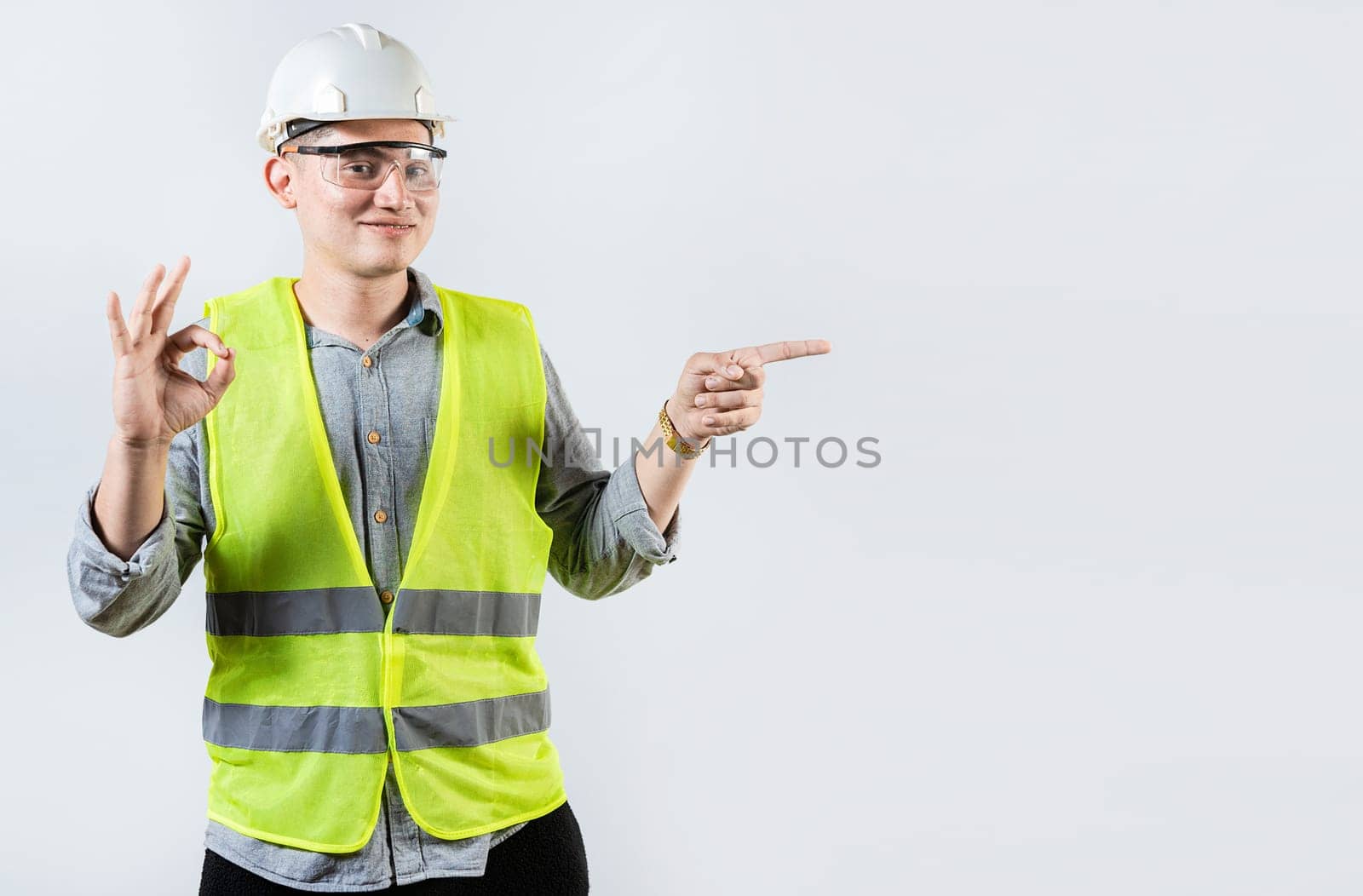 Portrait of male engineer recommending and pointing aside. Smiling engineer pointing and approving an advertisement