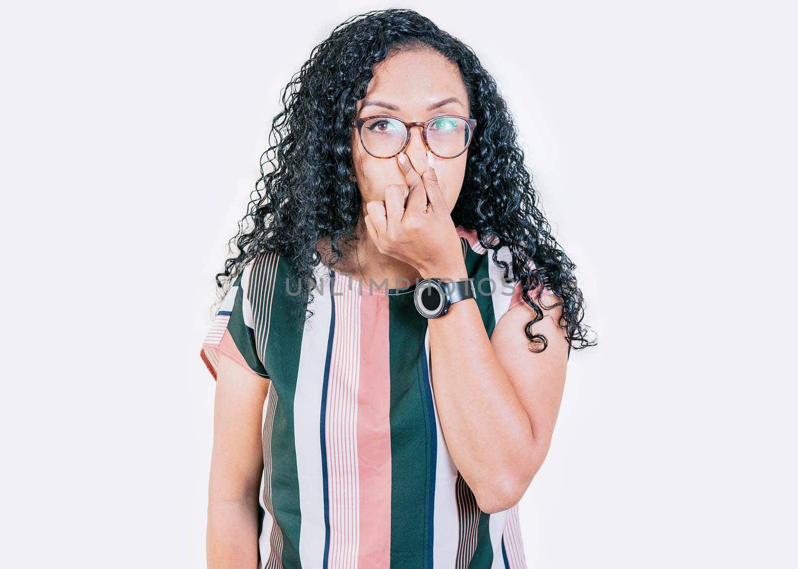 Displeased afro girl holding her nose isolated. Disgusted young afro woman covering nose. Woman in glasses covering nose from a bad smell isolated by isaiphoto