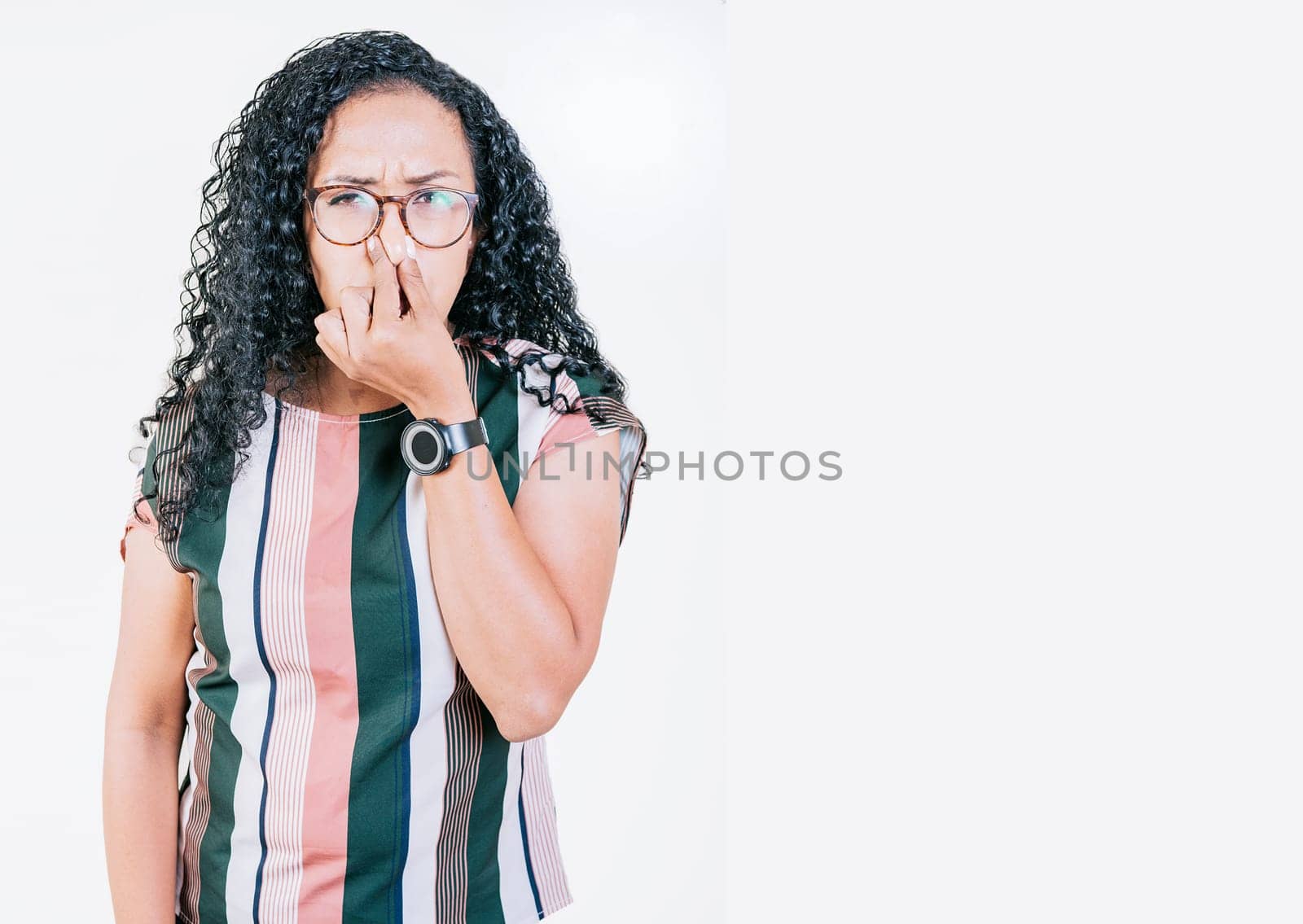 Disgusted young afro woman covering nose. Woman in glasses covering nose from a bad smell isolated. Displeased afro girl holding her nose isolated by isaiphoto