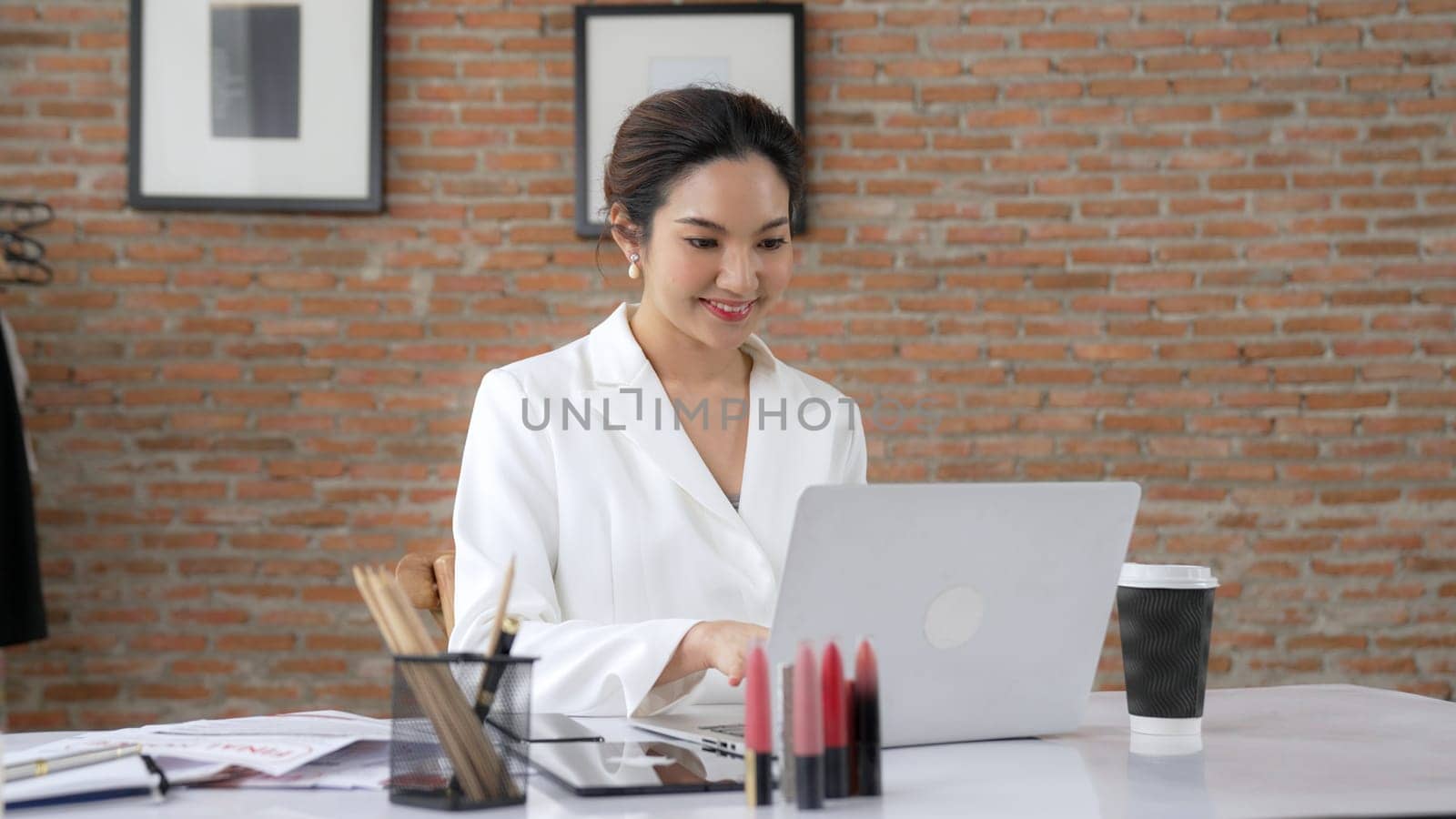 Young businesswoman sitting on the workspace desk using laptop. Vivancy by biancoblue