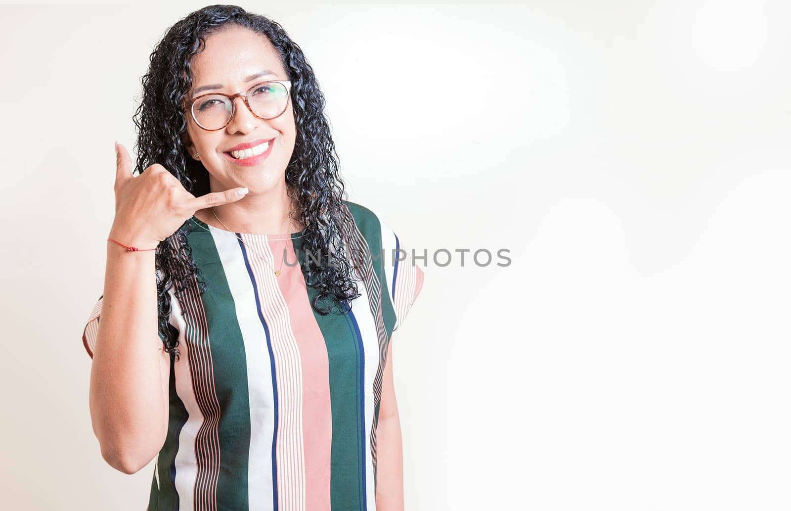 Happy girl in glasses gesturing call me with hand isolated. Latin woman in glasses gesturing call with fingers isolated.